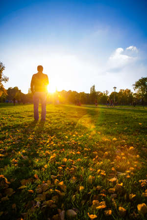 man watching the autumn sunset in a park の写真素材