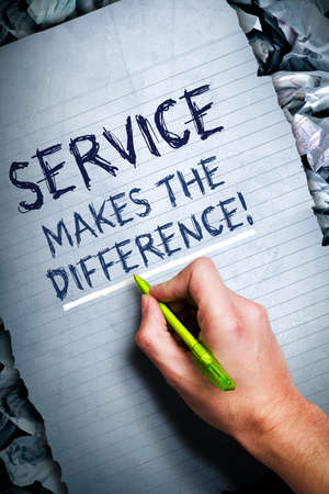 man writing the text service makes the difference, surrounded by a bunch of crumpled papers symbolizing that the final conclusion is found の写真素材