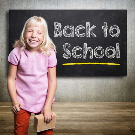 happy young girl writing \'back to school\' on a blackboard の写真素材