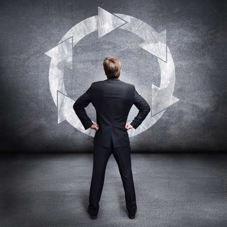 businessman looking at a cycle drawing on a wall