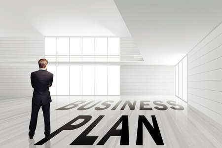 businessman standing in an empty office space with the message \business plan\ on the ground