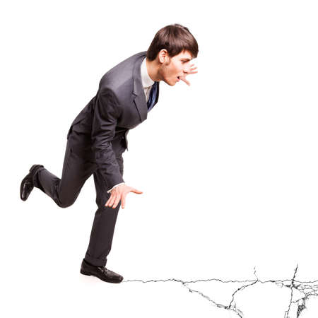 businessman balancing on cracking groundの写真素材