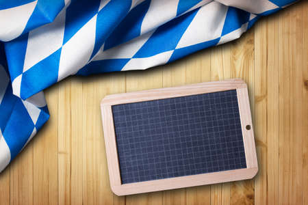 bavarian tablecloth on a wooden background with an empty blackboardの写真素材