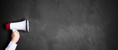 hand with a megaphone in front of an empty blackboardの写真素材