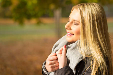 attractive blonde girl enjoying a park in autumnの写真素材