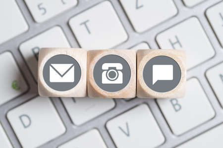 several contact options as icon on little cubes on a keyboardの写真素材