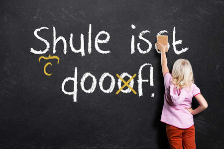 young girl correcting mistakes in the sentence "School is stupid" in Germanの写真素材