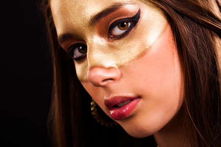 attractive young woman with a golden maskの写真素材