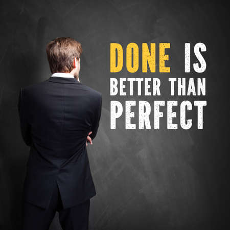 businessman standing in front of a chalkboard with the message Done is better than perfect