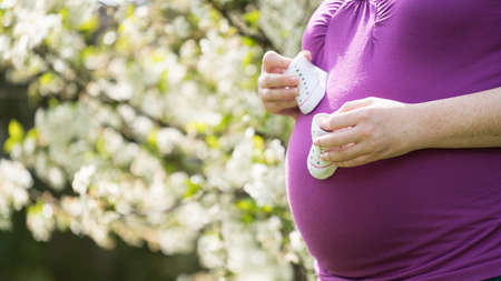 pregnant woman with tiny baby shoesの写真素材