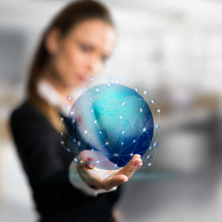 businesswoman presenting a holographic globe in front of an office sceneの写真素材