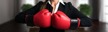 attractive businesswoman with boxing gloves ready for a fight in front of an apartment