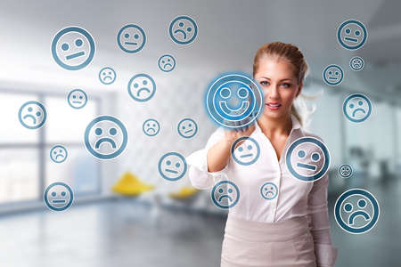 businesswoman is selecting a good mood smiley out of many sad onesの写真素材