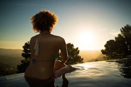 woman in an infinity pool watching sunsetの写真素材