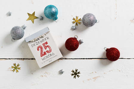 tear-off calendar with 25th of december on top and christmas decoration on a wooden surfaceの写真素材