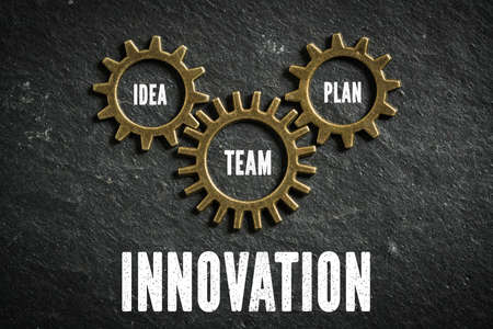 cogwheels symbolizing a connection of topics and the message "idea, team, plan and innovation" on slate backgroundの写真素材