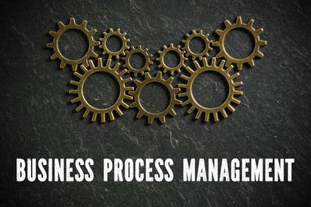 cogwheels symbolizing complex machinery and the word business process management on slate background