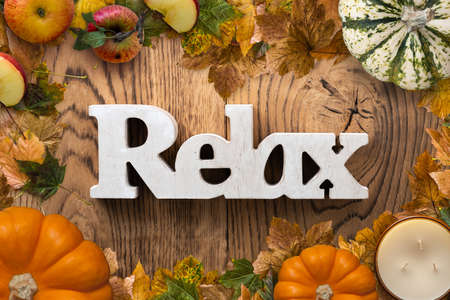 frame of leaves and pumpkins on wooden background and the word "relax"の写真素材
