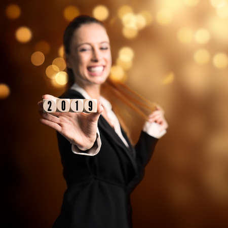 smiling woman holding cubes with the numbers 2019 in front of the camera