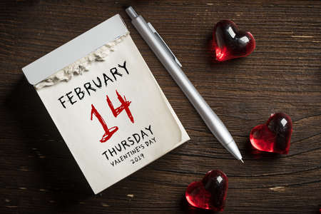 tear-off calendar with Valentine's Day 2019 on top,  surrounded by hearts on wooden backgroundの写真素材