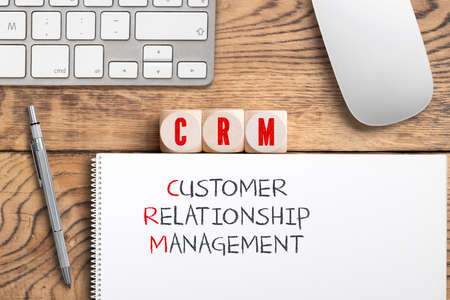cubes showing the acronym "CRM" and the explanation "customer relationship management" on wooden backgroundの写真素材