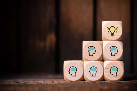 many people together having an idea symbolized by icons on cubes on wooden backgroundの写真素材