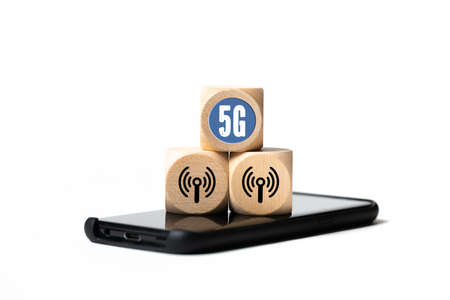 Technology name 5G on a cube laying on a smartphone isolated in whiteの写真素材