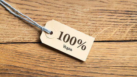 Hangtag with title "100% vegan" on wooden backgroundの写真素材