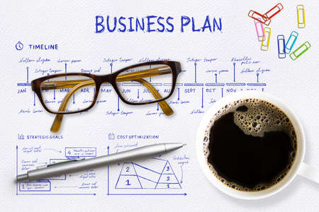 Close-up view from above of a professional desk with a cup full of hot coffee, next to eyeglasses,...