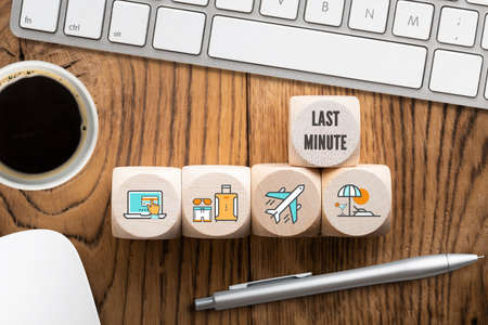 Last minute online travel specials concept with a row of wooden blocks with icons depicting laptop,...
