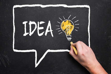 hand is drawing speech bubble with text IDEA on chalkboard