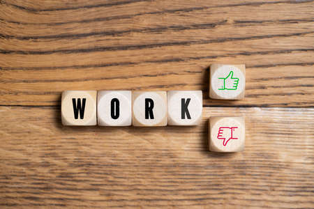 cubes with word "WORK" and a thumb up and down icon on wooden backgroundの写真素材