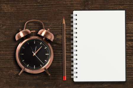 clock with pen and empty notepad on wooden backgroundの写真素材