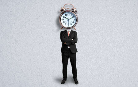 alarm clock as a head of a businessman on paper backgroundの写真素材