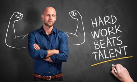 businessman and the message hard work beats talent in front of a blackboard