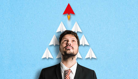 businessman with idea symbolized by a red airplane that is faster than the others in front of paper...