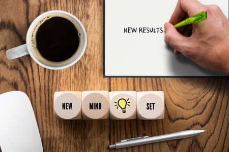 cubes with words and hand with pen writing the message "new mindset - new result" on wooden backgroundの写真素材
