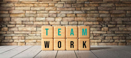 cubes with the word TEAMWORK in front of a brick wall - 3D rendered illustration