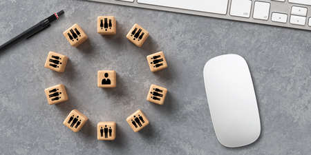 cubes with people symbols forming a circle around a single person on concrete backgroundの写真素材