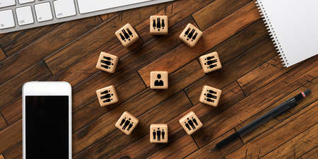 cubes with people symbols forming a circle around a single person on wooden backgroundの写真素材