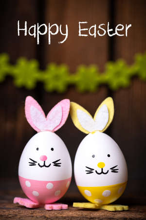 Easter Eggs with bunny ears and message Happy Easter on wooden background