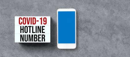 lightbox with text COVID-19 HOTLINE NUMBER with smartphone on concrete background
