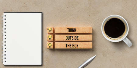 boxes with text THINK OUTSIDE THE BOX and a notepad, coffee and a pen on paper backgroundの写真素材