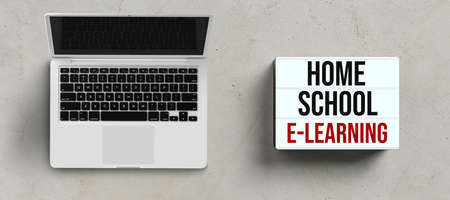 laptop and lightbox with message HOME SCHOOL E-LEARNING on concrete background