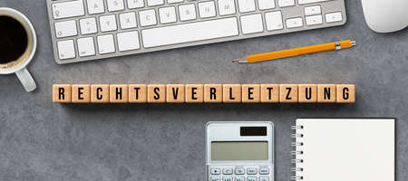 cubes with message RIGHT VIOLATION in German with computer equipment on concrete background