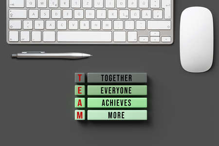blocks with message TOGETHER EVERYONE ACHIEVES MORE - TEAM with computer equipment on grey...