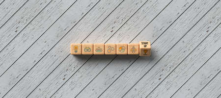 cubes with word START-UP and tech icons on wooden background - 3D rendered illustration