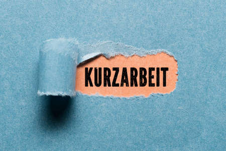 torn paper revealing a document with the German text for SHORT TIME WORKの写真素材