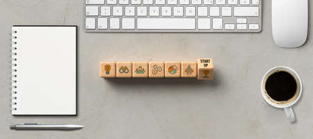 cubes with word START-UP and tech icons on concrete background