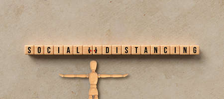 cubes with the message SOCIAL DISTANCING and miniature wooden mannequin on paper background